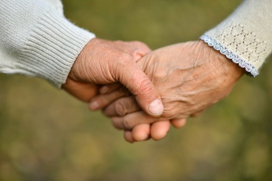 elderly couple holding hands in beautiful park