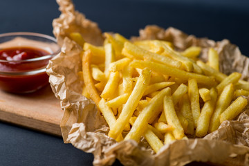 fried potatoes on wrapping paper with ketchup