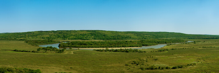 Panorama of the landscape in the early autumn. Landscape in the form of a river, hills and meadows. Panorama of nature against a clear blue sky.