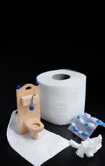 Wooden toy toilet, capsules and paper on black
