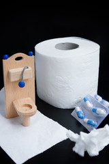 Wooden toy toilet, capsules and paper on black