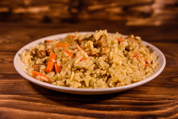 Ceramic plate with pilaf on wooden table