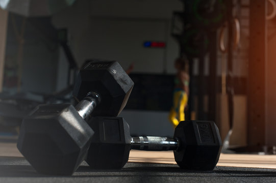 Workout with dumbbells. Blurred gym background.