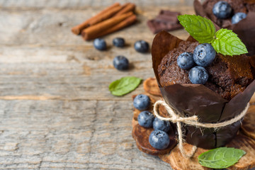 Chocolate muffin with mint and blueberries on wooden stand Copy space
