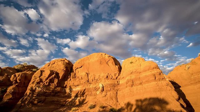 Time lapse viewing red rocks in the Escalante Utah desert as the shadows move up the cliffs and clouds move through the sky at sunset.