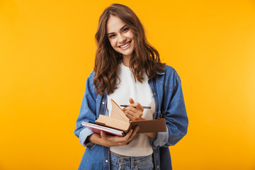 Young woman posing isolated over yellow background reading book take notes.