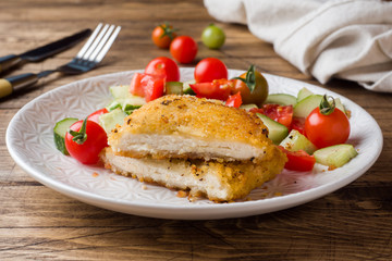 Chicken cutlet and cucumber salad with tomatoes on a wooden table