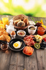 breakfast on table with bread buns, croissants, coffe and juice.