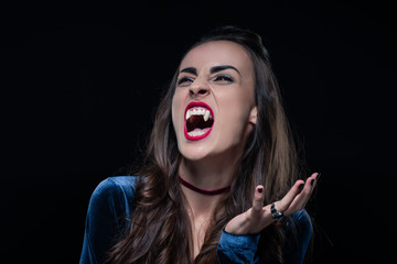 grim woman showing vampire fangs isolated on black