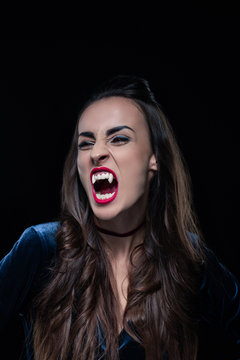 beautiful woman showing vampire teeth isolated on black