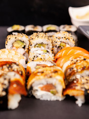 Mix variety of sushi rolls on black stone backgorund in studio