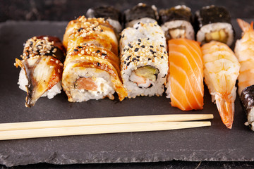 Variety mix of sushi rolls on black background in studio photo