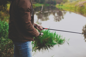 Young fisherman is fishing in river with spinning