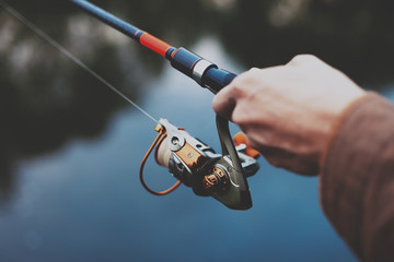 Young fisherman is fishing in river with spinning