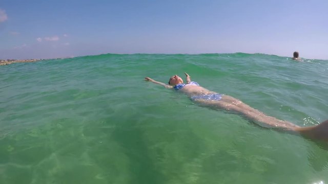 Красивая молодая женщина Кавказа в бикини, плавающие на поверхности воды в кристально чистый бирюзовый цвет моря