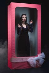 mystic vamp woman posing in doll box with bow