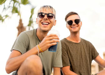 two guys drink cocktails on a tropical beach