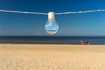 Light bulb on the wire on the beach