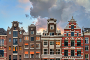 Fototapeta na wymiar Facades of typical dutch manor houses at the UNESCO world heritage canals of Amsterdam, The Netherlands, with a summer sunset sky 