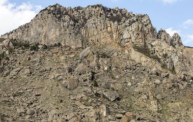 mountain rock high stone wall windblown group of cobblestones at the foot of a steep climb dangerous walk