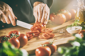 Chef slicing tomatoes in a ray of sunlight