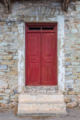 Fototapeta na wymiar Red door of stony house