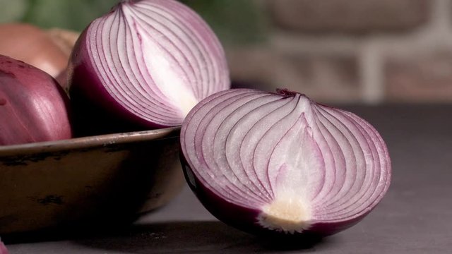 Fresh whole onions in assorted colors and parsley in a small rustic frying pan on kitchen counter top.