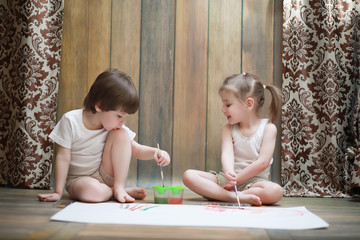Obraz na płótnie Canvas Little children paint on a large sheet of paper