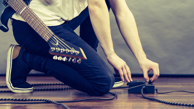 Man adjusting guitar effects pedal