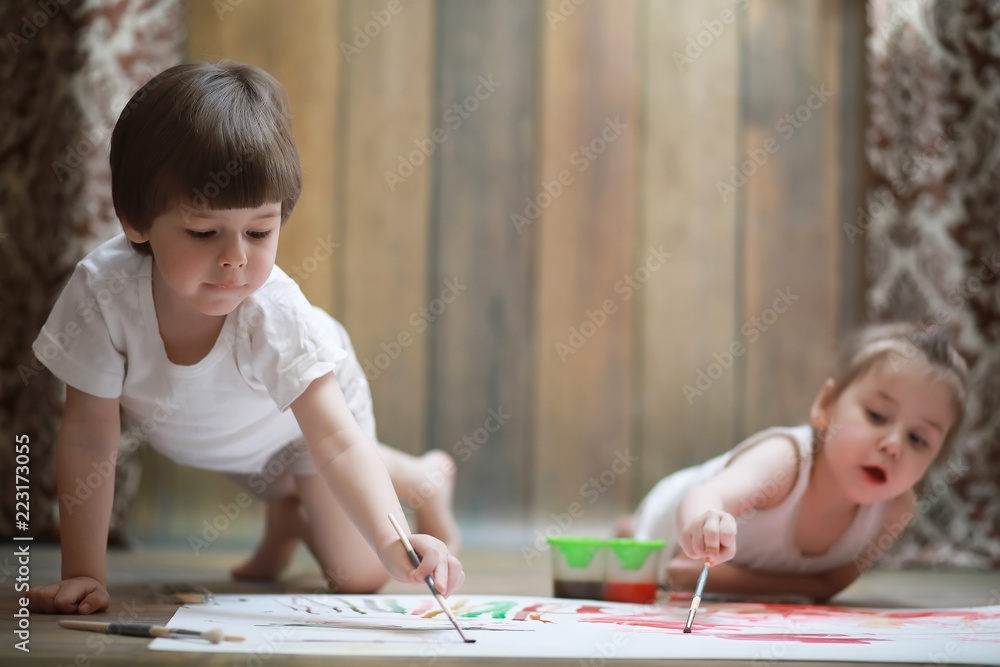 Wall mural little children paint on a large sheet of paper