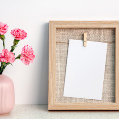 A square photo of terrazzo desk with wooden frame mockup and pink carnations in a notched vase