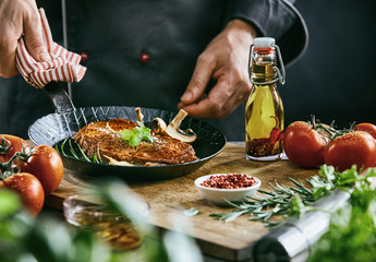 Chef in black suit holding dark metal skillet