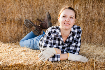 Portrait of positive woman farmer lying on strawstack resting during work