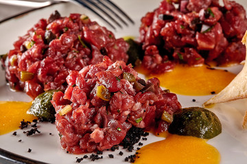 Chips bread with tartare vs carpaccio of beef on table at the restaurant. Molecular modern cuisine. Close-up