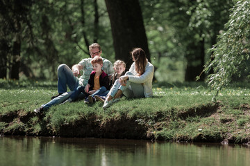 parents with children sitting on the grass in the city Park