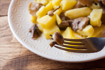 Fried potatoes with mushrooms and onions. Wooden table
