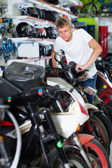 Fototapeta na wymiar Young attentive man motorcyclist choosing the bike in the shop