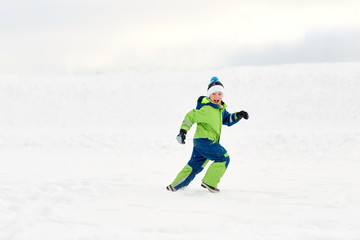 childhood, leisure and season concept - happy boy having fun outdoors in winter