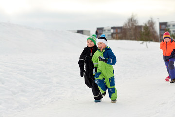 Fototapeta na wymiar childhood, leisure and season concept - group of happy little kids in winter clothes running outdoors