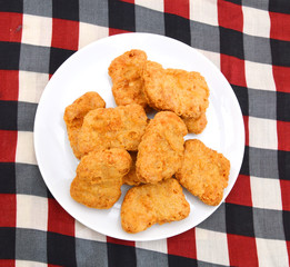 Fried chicken nuggets isolated in white plate on tablecloth background