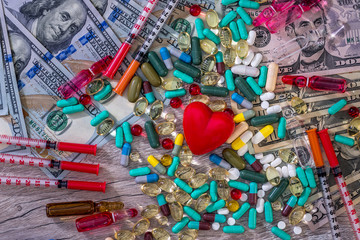 Medical conception on wooden background with dollars, tablets and syringes