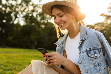 Smiling young girl in summer hat sitting outdoors