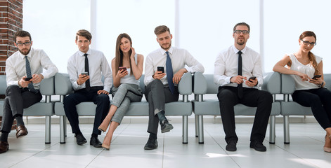 group of young employees sitting in a row in the office waiting room