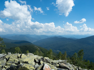 Carpathians mountains, west Ukraine. Pile of grey natural stones. White clouds flowing in blue sky....
