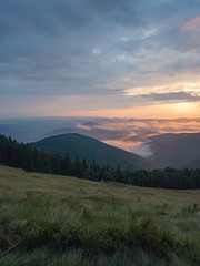 Naklejka na ściany i meble Carpathians landscape in august, west Ukraine. Sundown in mountains at summer. Ukrainian nature background. The sky covered with grey clouds illuminated by the sun. Blurred background