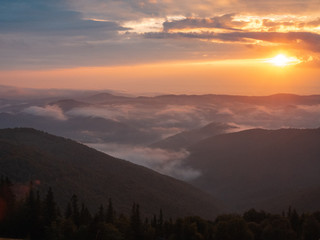 Landscape of Carpathians mountains, west Ukraine. Low clouds flowing round mountains peaks. The sun...
