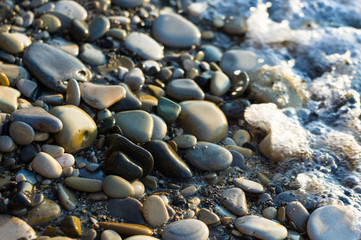 pebble stones on the sea beach, the rolling waves of the sea with foam