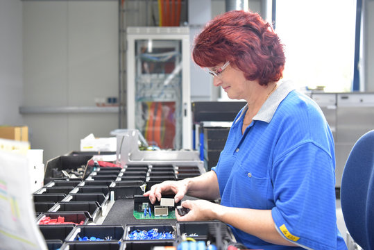 Arbeiterin in der Ferigung von elektronischen Bauteilen in einer modernen Fabrik // Worker in the production of electronic components in a modern factory