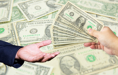 hand hold many dollar banknotes and another one act receive that money with dollar background. corruption concept.US Dollor Currency in hand.