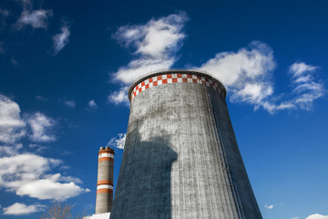 one huge and one tall pipes. polution, smoking pipes against blue sky